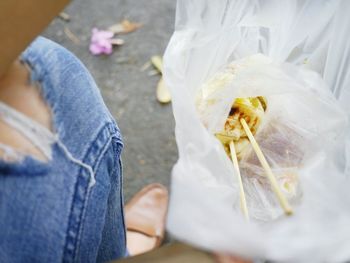 Low section of man holding food while sitting outdoors