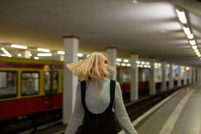 Woman with blond hair standing at railroad station platform