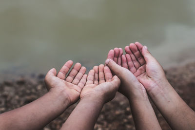 Cropped hands gesturing against lake