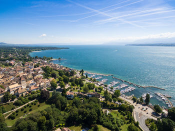 High angle view of townscape by sea against blue sky