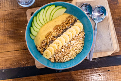 Healthy smoothie bowl breakfast with granola, cut banana, sliced apples, and various types of nuts