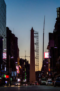 City street and buildings against sky at dusk