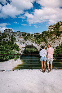 Rear view of couple walking on water against sky