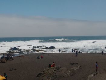 Panoramic view of people on beach against sky