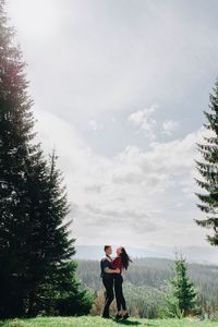 Side view of young couple standing face to face in forest