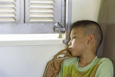 Thoughtful boy sitting by window in train