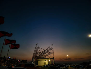 Silhouette cranes at harbor against sky during sunset