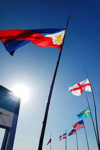 Low angle view of various flags against sky on sunny day