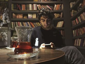 Young man using mobile phone while sitting on table