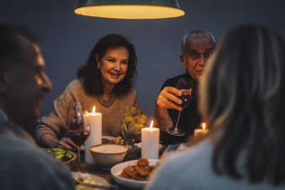 Smiling retired woman enjoying dinner with friends at party