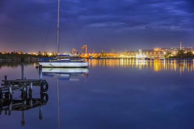 Sailboats moored in harbor at dusk