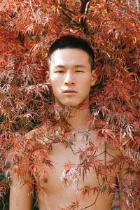 Portrait of shirtless man standing by plants during autumn