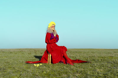 Woman with red umbrella on field against clear sky