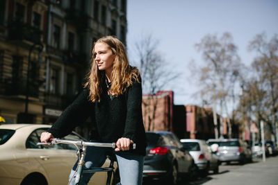 Young man with bicycle on street in city