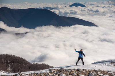 Man standing on snowcapped mountain against sky