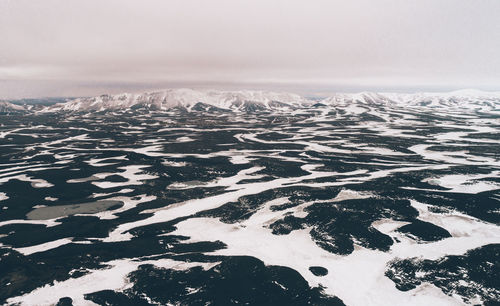 Aerial view of snow covered land and sea against sky