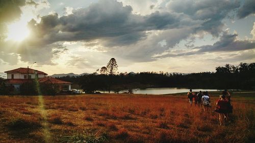 People on grass against cloudy sky