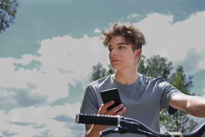 Handsome teenager riding a bike and holding a smartphone. using messenger or social media or texting