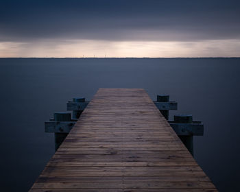 Wooden pier over lake against sky at dusk