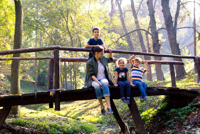 Full length of mother and kids sitting on footbridge