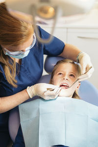 Female dentist examining girl at clinic