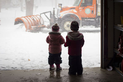 Rear view of siblings in warm clothing standing at store entrance