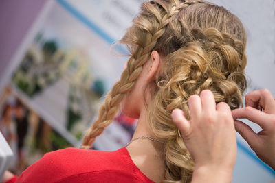 Close-up of female hairstylist holding blond customers hair at salon
