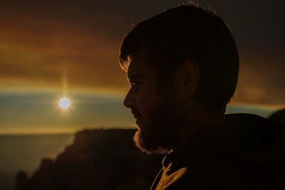 Side view of a man looking at sunset