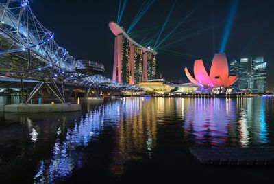 Laser light display on illuminated marina bay sands by sea at dusk