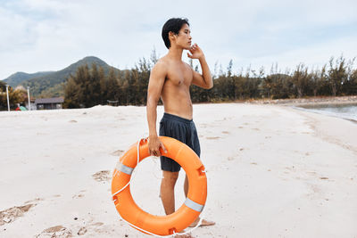 Side view of shirtless man standing at beach