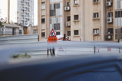 Road sign on street against buildings in city