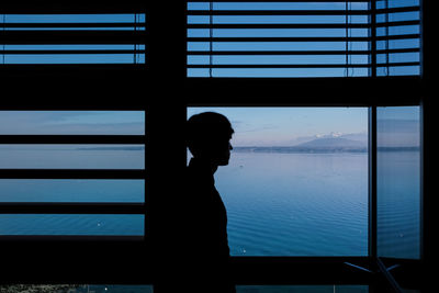 Silhouette man looking through window