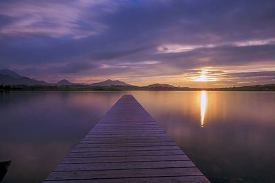 Pier over lake against sky during sunset