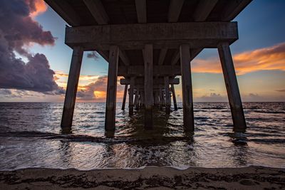 Pier on sea against sky during sunset