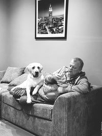 Man with dog sitting on sofa at home