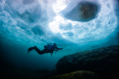 Full length of scuba diver swimming in frozen sea