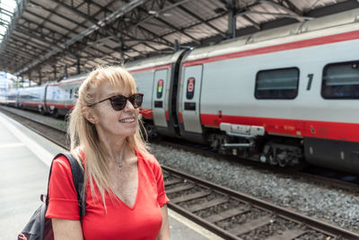 Mature adult woman with sunglasses waiting for train on platform