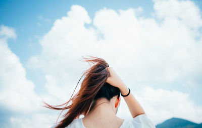 Young woman looking away against sky