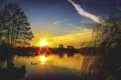 Silhouette trees by lake against sky during sunset