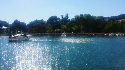 Boats moored in calm blue sea against clear sky