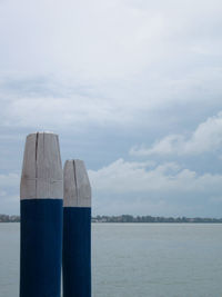Wooden posts on sea against sky