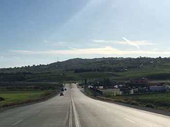 Empty road amidst landscape against sky