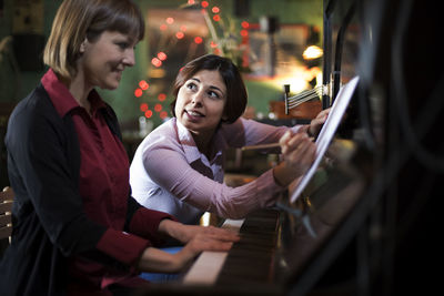 Woman teaching piano to student at home