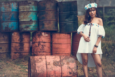 Fashionable woman standing against old containers on field