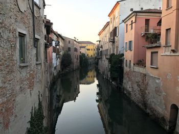 Canal amidst buildings in town against sky