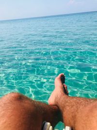 Low section of man in swimming pool against sea