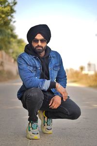 Full length of young man wearing turban crouching on road