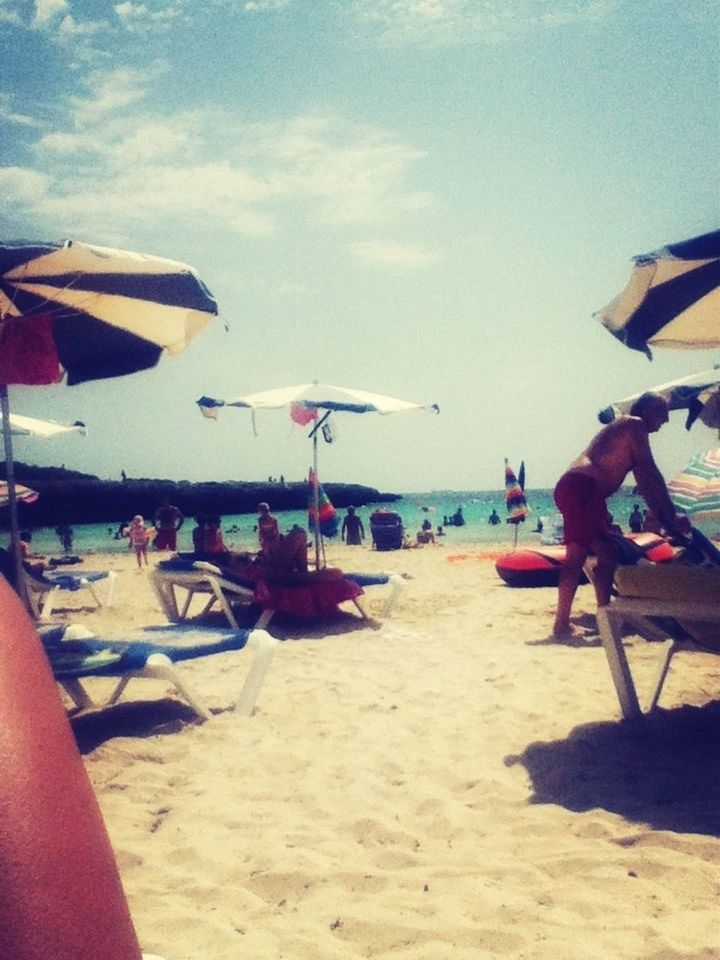 beach, sand, sea, shore, sky, beach umbrella, parasol, vacations, lounge chair, leisure activity, sunshade, horizon over water, chair, water, sunlight, deck chair, relaxation, lifestyles, summer