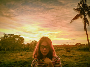 Portrait of woman on field against sky during sunset