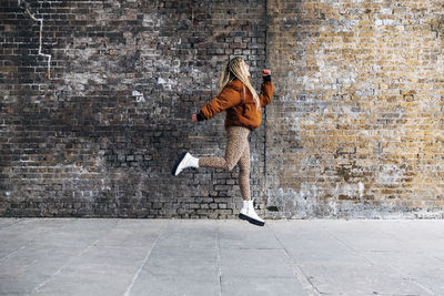 Woman looking away while running against wall